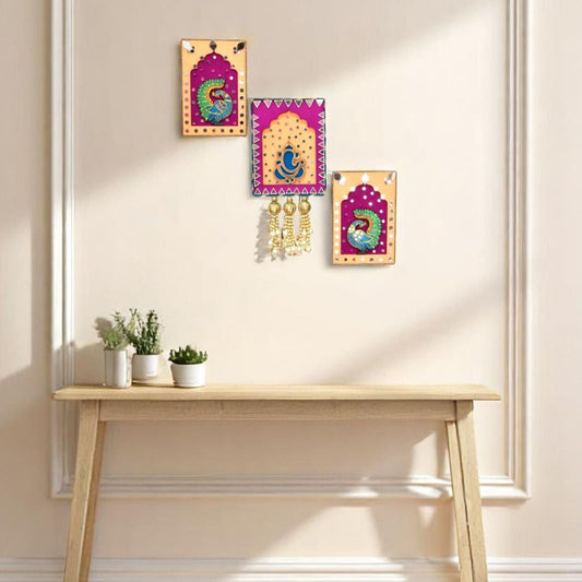 Decorative wall art and earrings on a wall above a wooden table with plants.