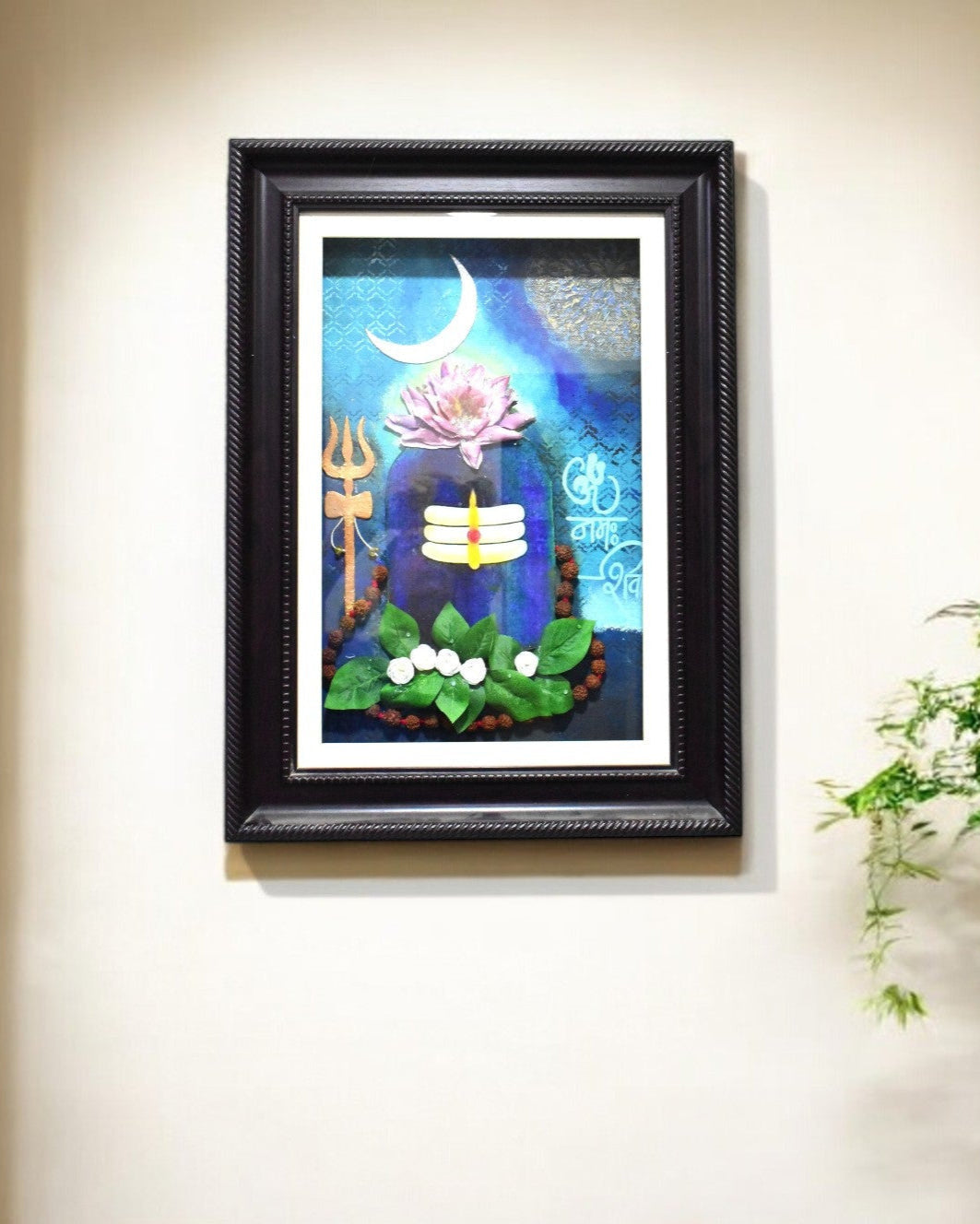 Framed Shiva artwork on a wall with a plant to the right