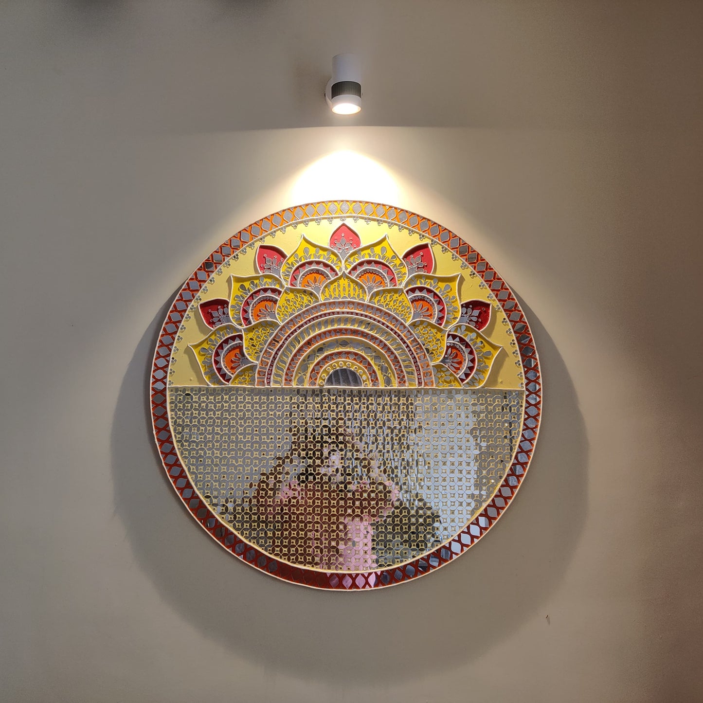 Circular mosaic artwork on a wall with a light fixture above