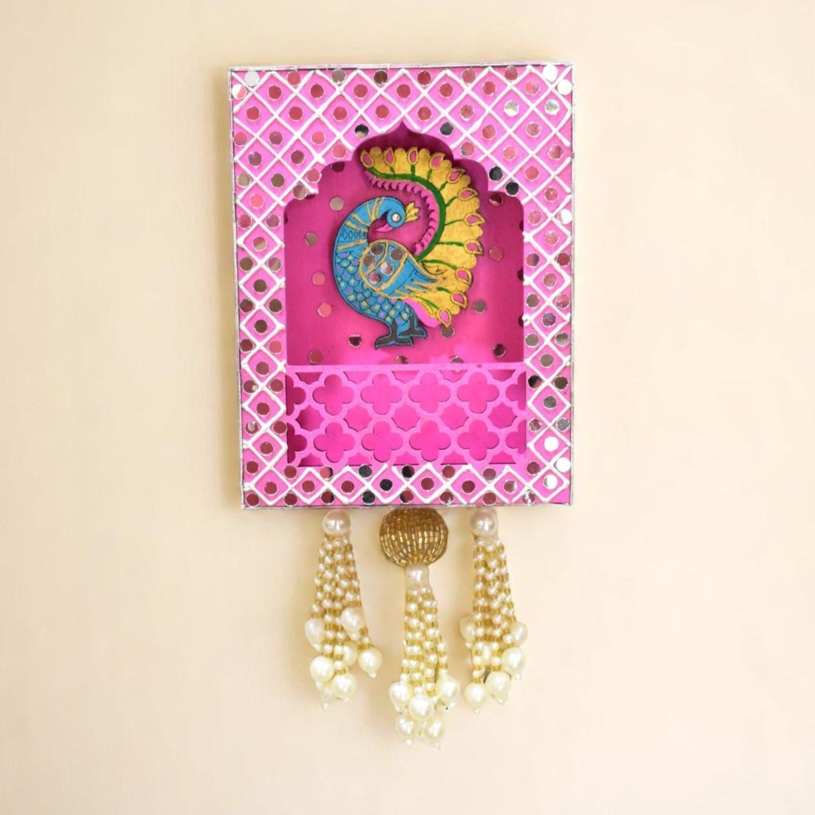 Decorative wall hook with peacock design and pink frame on a beige background