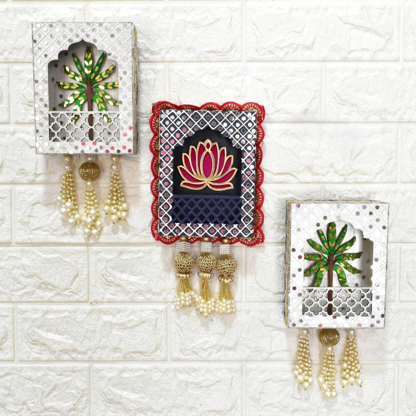 Decorative wall hangings with floral designs and tassels on a textured white wall.