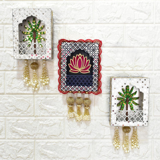 Decorative wall hangings with floral designs and tassels on a textured white wall.