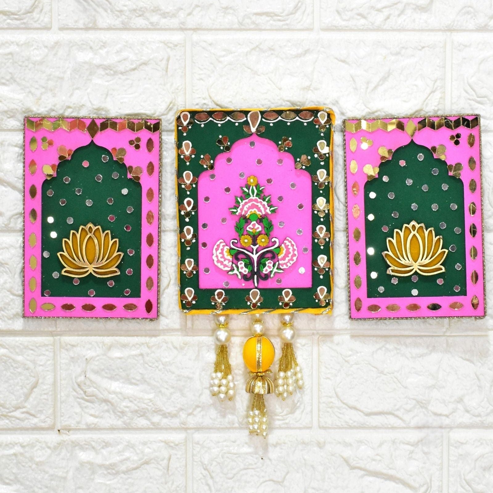 Decorative wall hanging with pink and green panels featuring floral designs on a white tiled background.