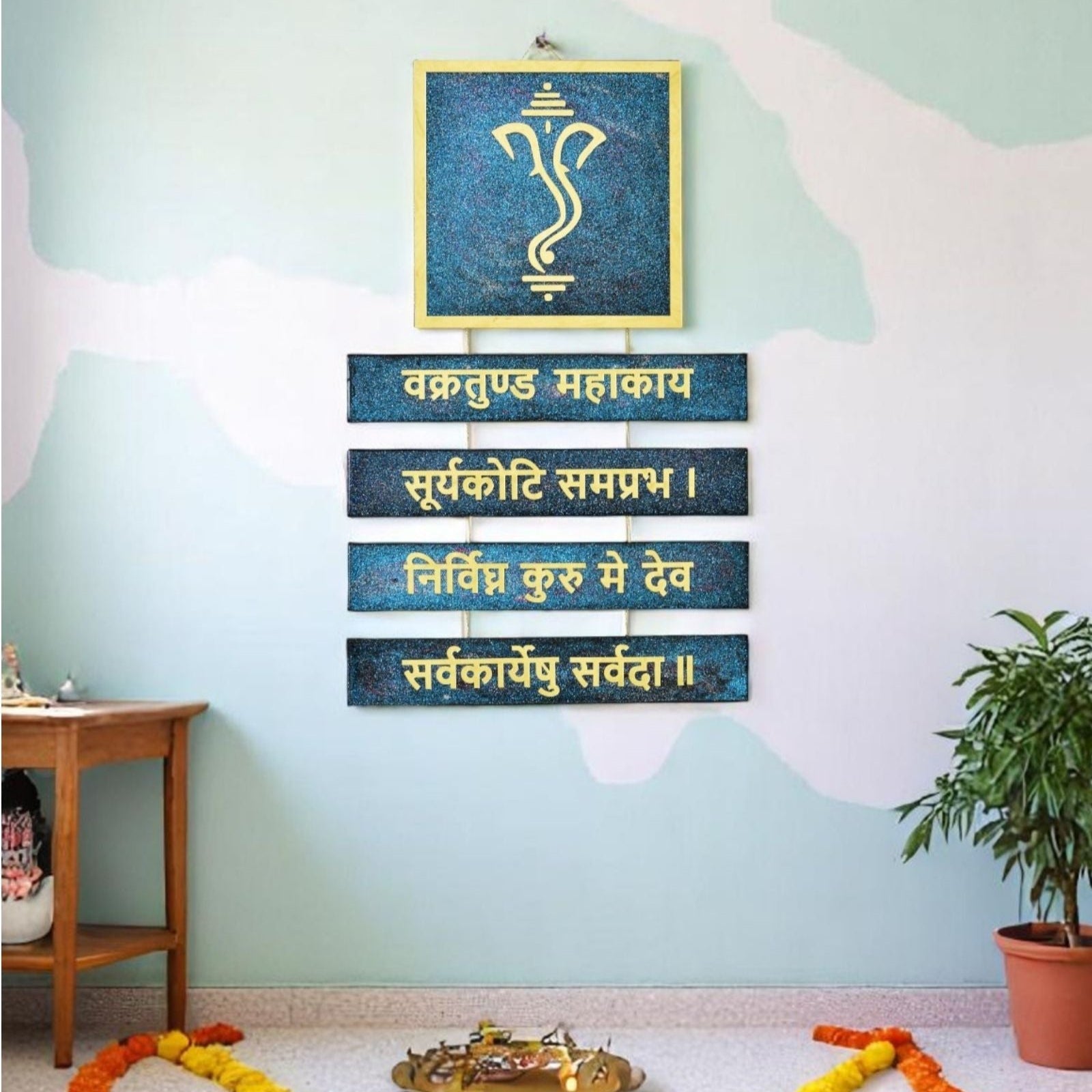 Decorative wall art with Ganpati Mantra Sanskrit text on a light blue wall.