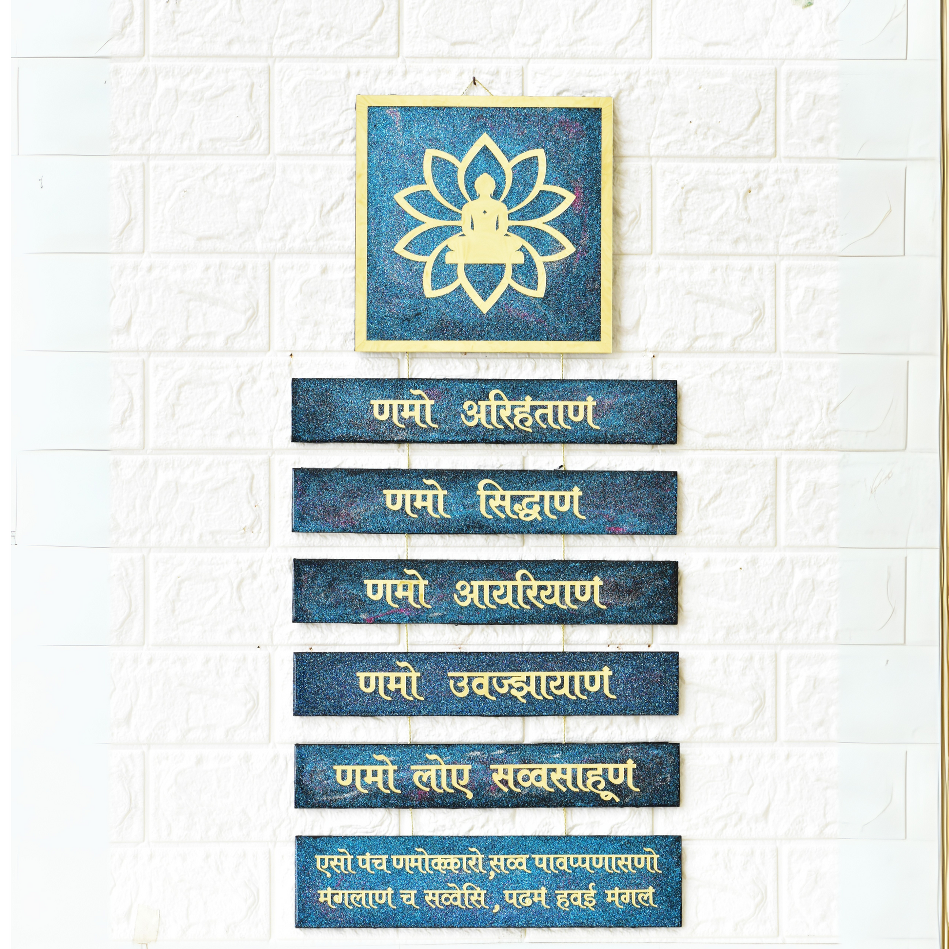 Set of blue plaques with gold text and a framed lotus flower on a white brick wall.