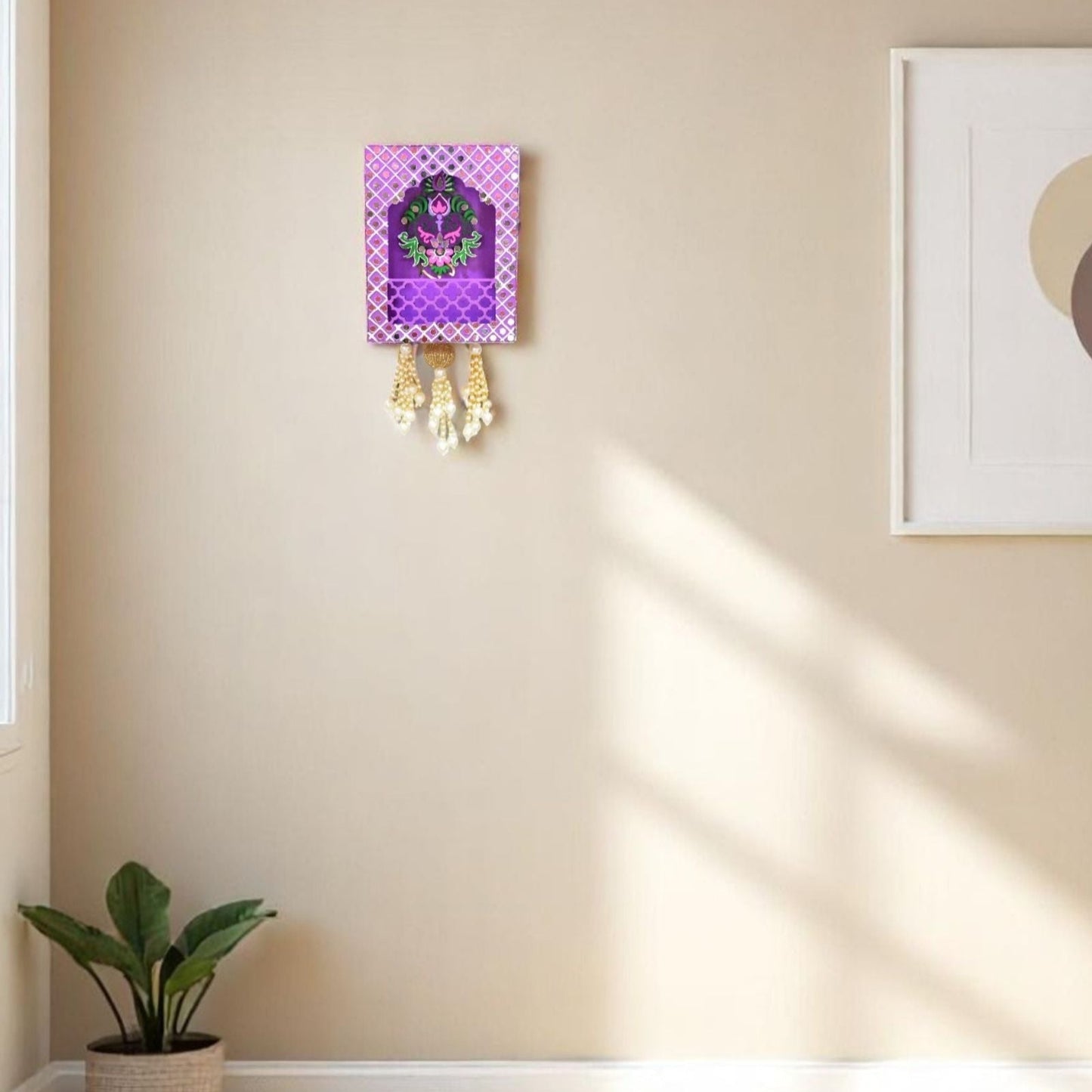 Decorative wall hanging with purple frame and pink floral design on a beige wall.