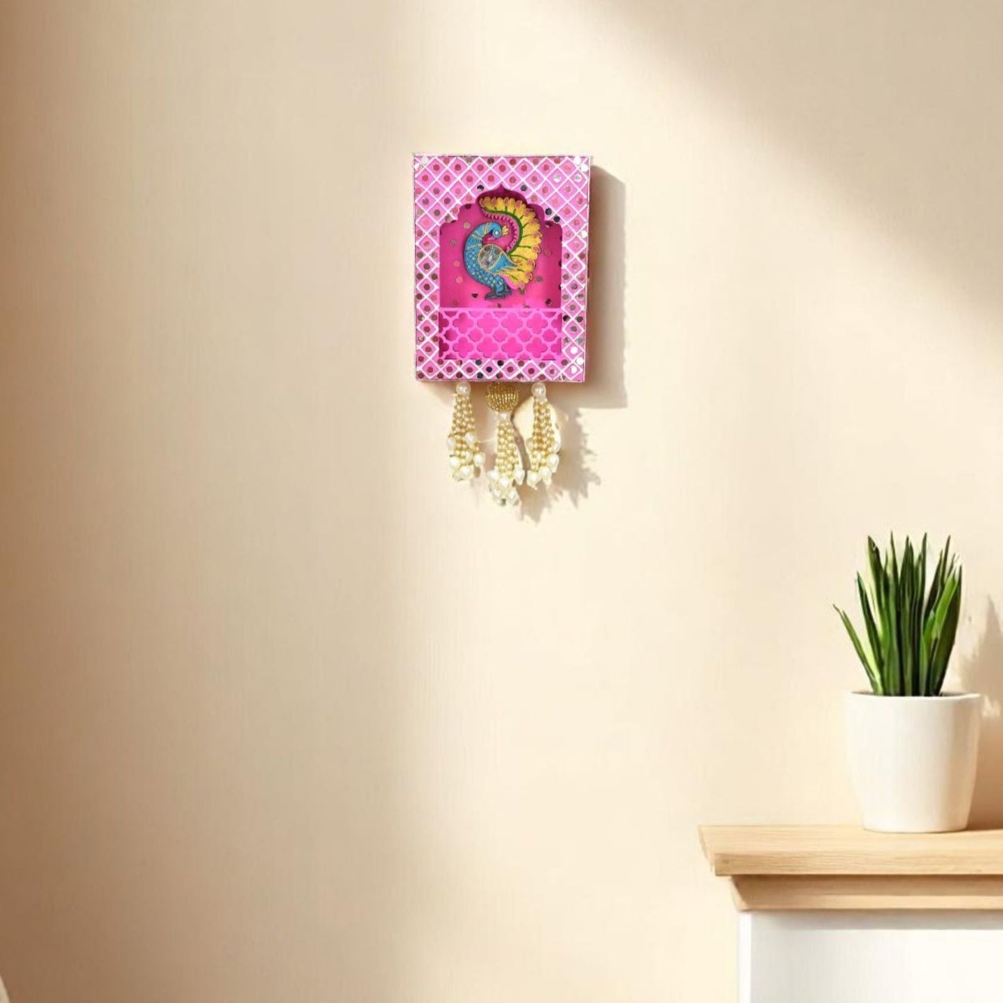 Decorative wall hanging with a colorful design on a beige wall next to a small plant.