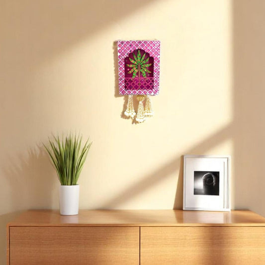 Decorative wall light fixture on a beige wall with a wooden cabinet and plant in the foreground.