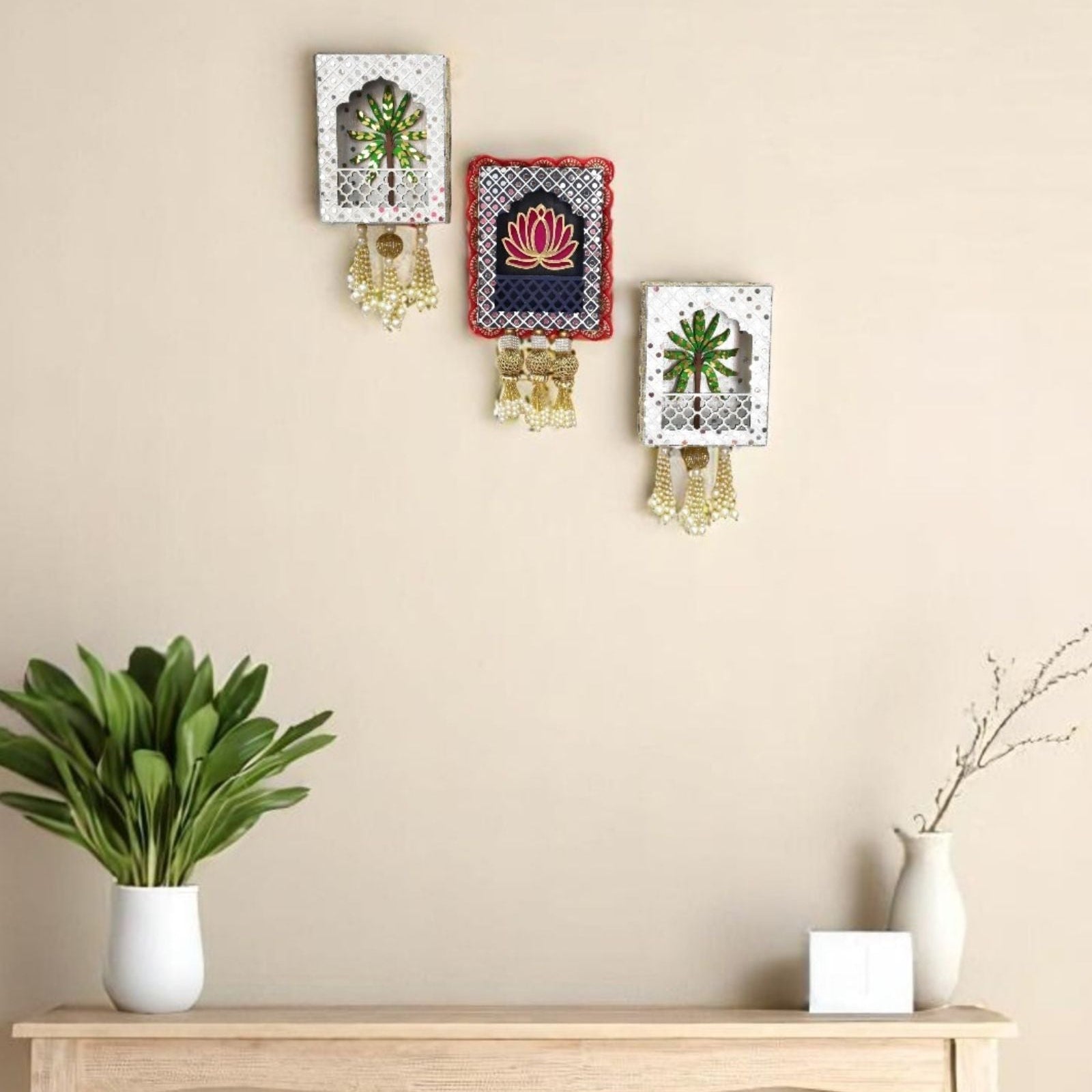 Decorative wall art pieces on a beige wall with a wooden console table and plants.