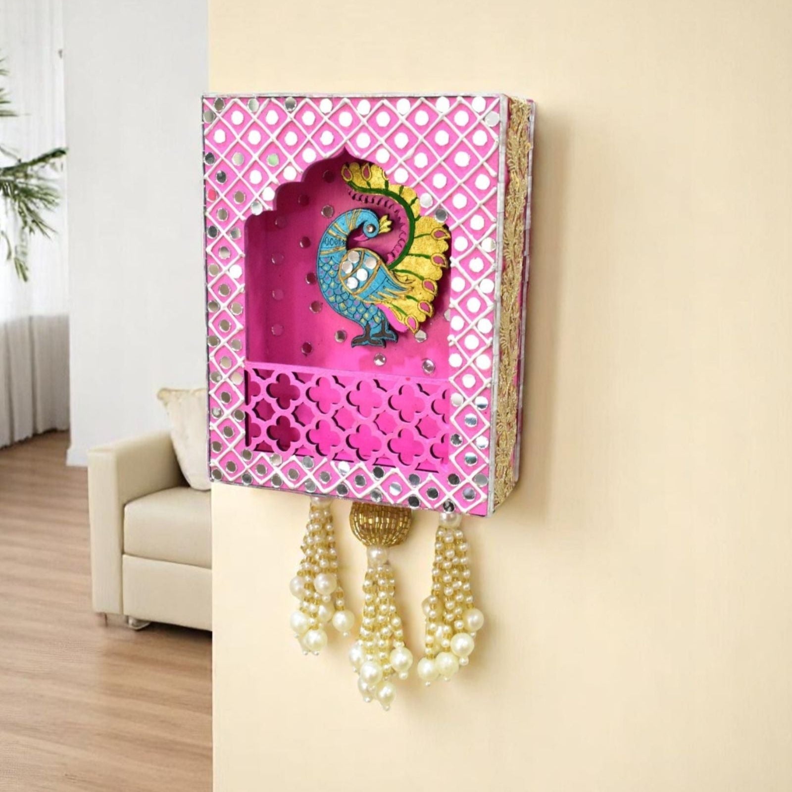 Decorative wall shelf with peacock design and hanging beads on a beige wall.