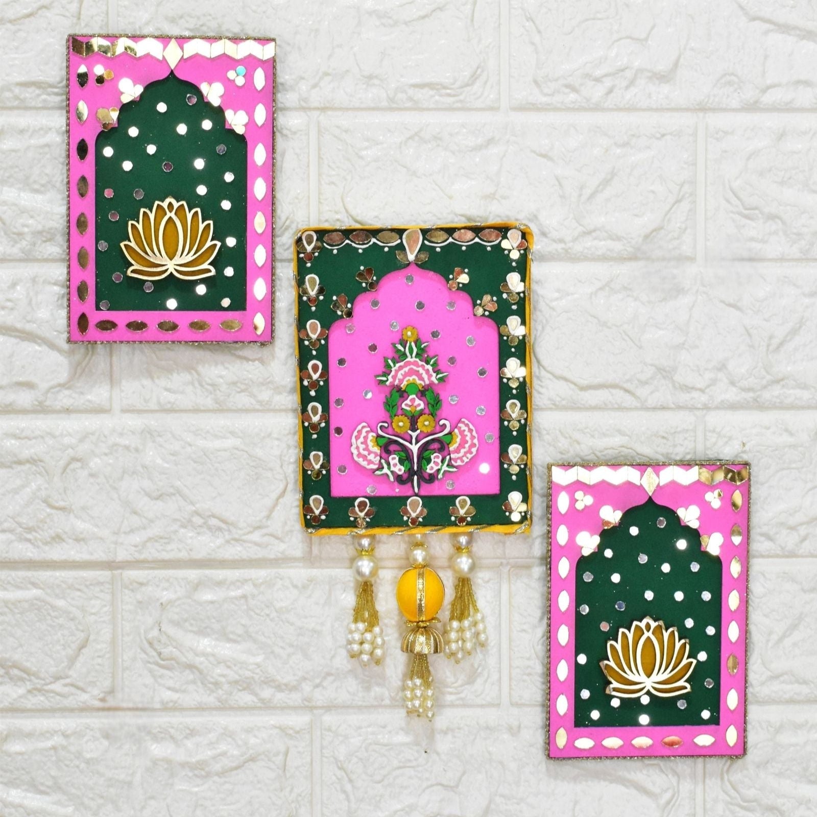 Decorative wall hangings with pink and green designs on a textured white wall.