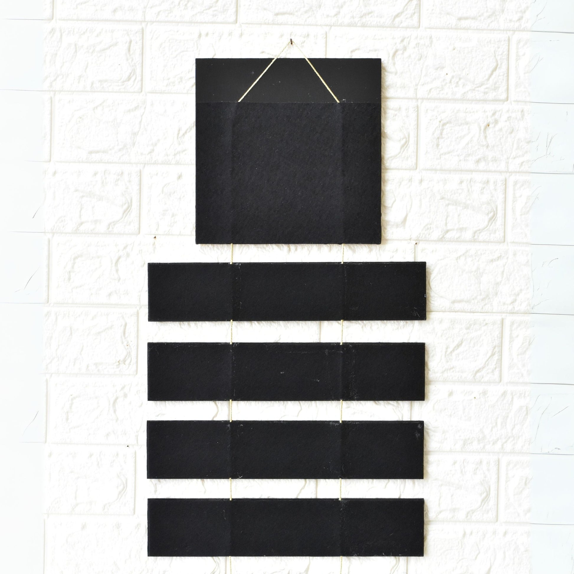 Set of black rectangular tiles hanging on a textured white wall