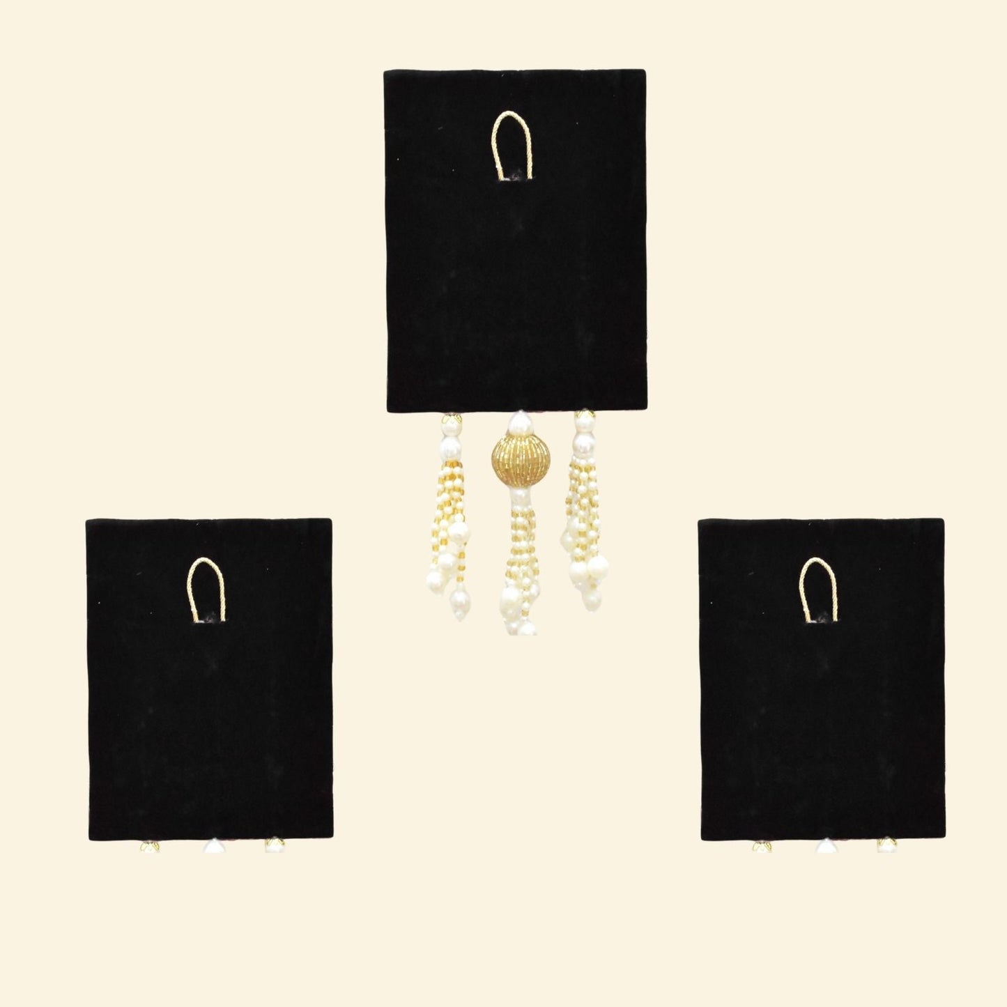 Black velvet earring display with gold and pearl earrings on a beige background