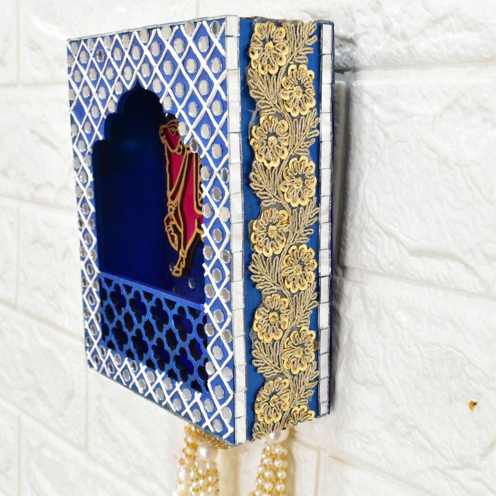 Blue decorative wall jharokha hanging with a cow in the centre and mirror and pearl beads.