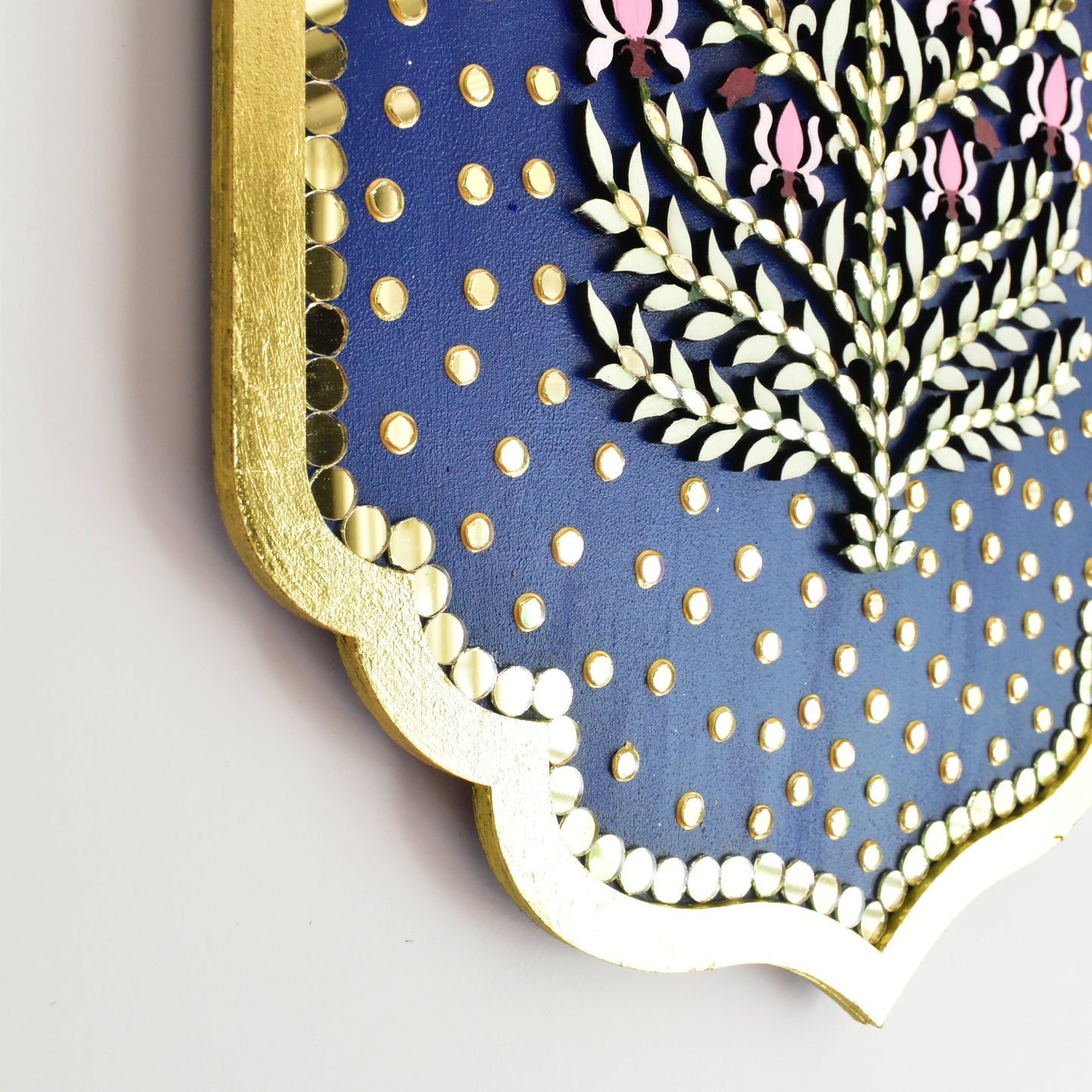 Close up of blue floral wall art with lotus floral design and gold mirror accents on a blue background