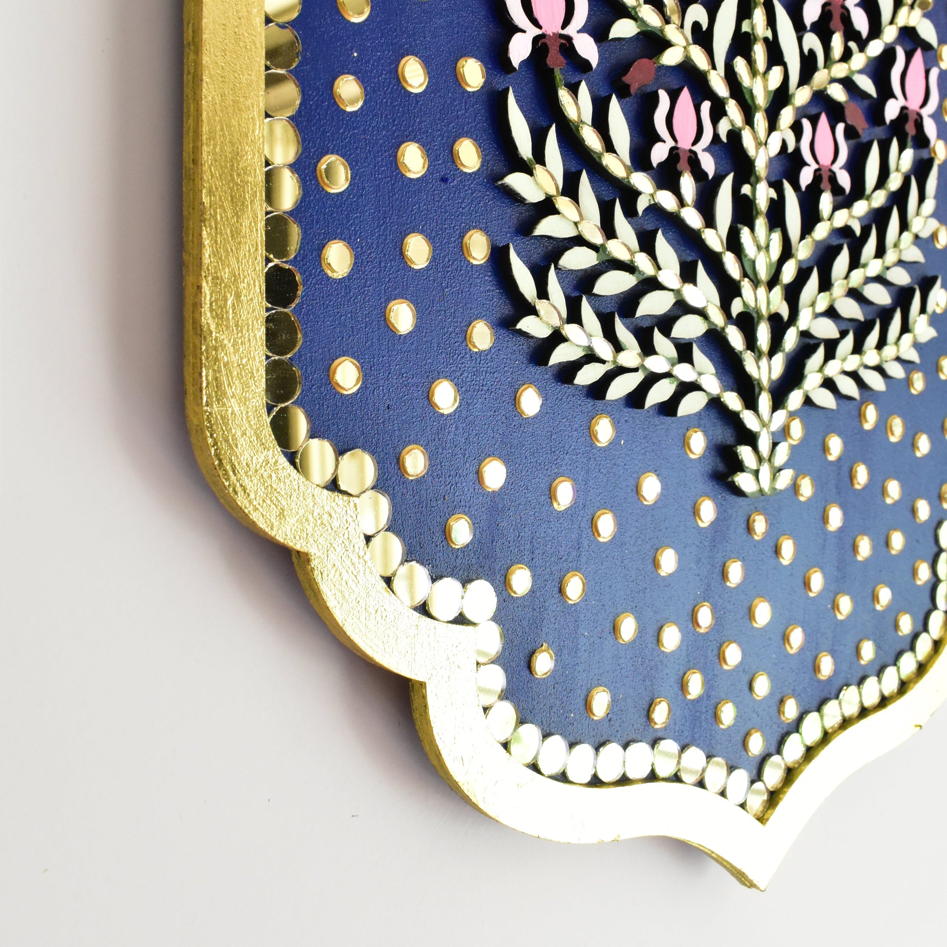 Close up of blue floral wall art with lotus floral design and gold mirror accents on a blue background
