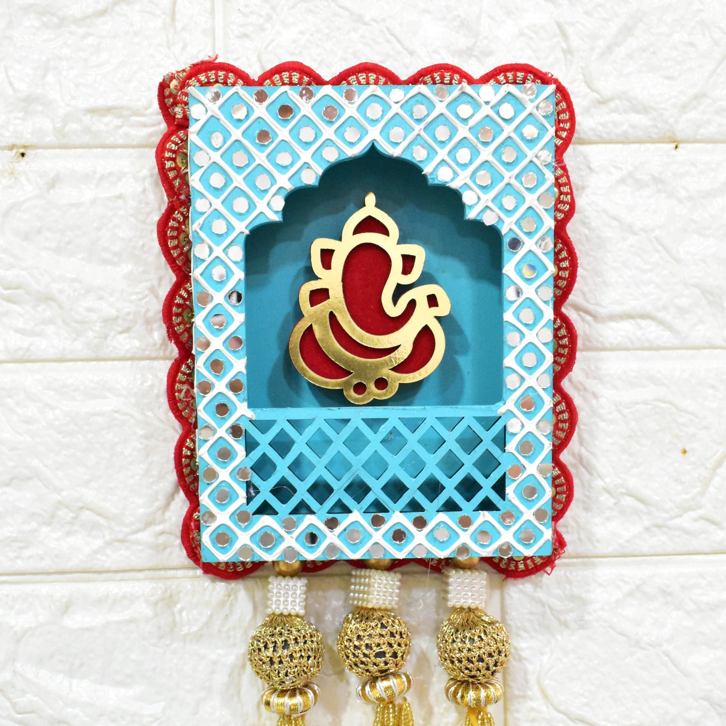 A wall hangings featuring Lord Ganesha in blue, red, and gold colors, with pearl tassels.