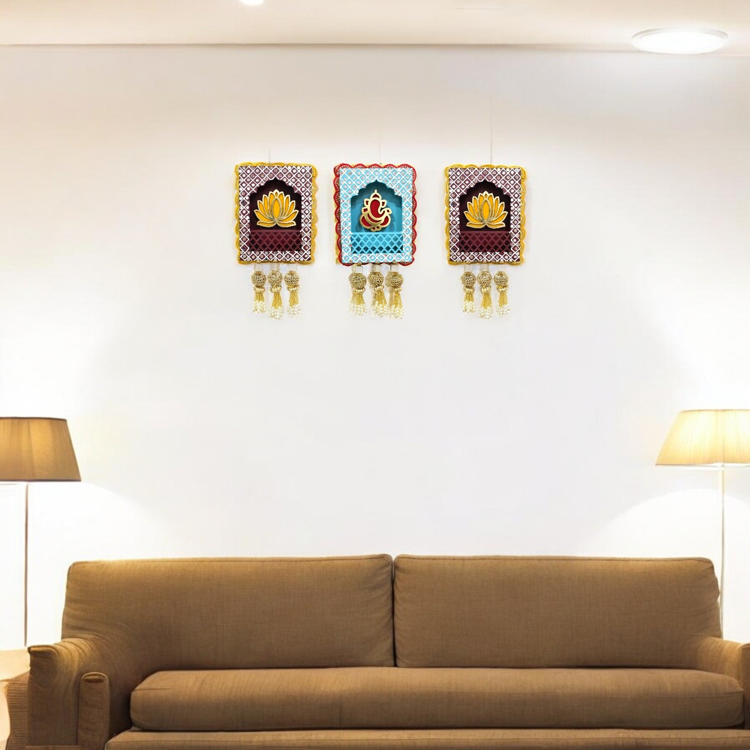 A set of three handcrafted wall hangings featuring Lord Ganesha with a lotus flower design on a living room wall.