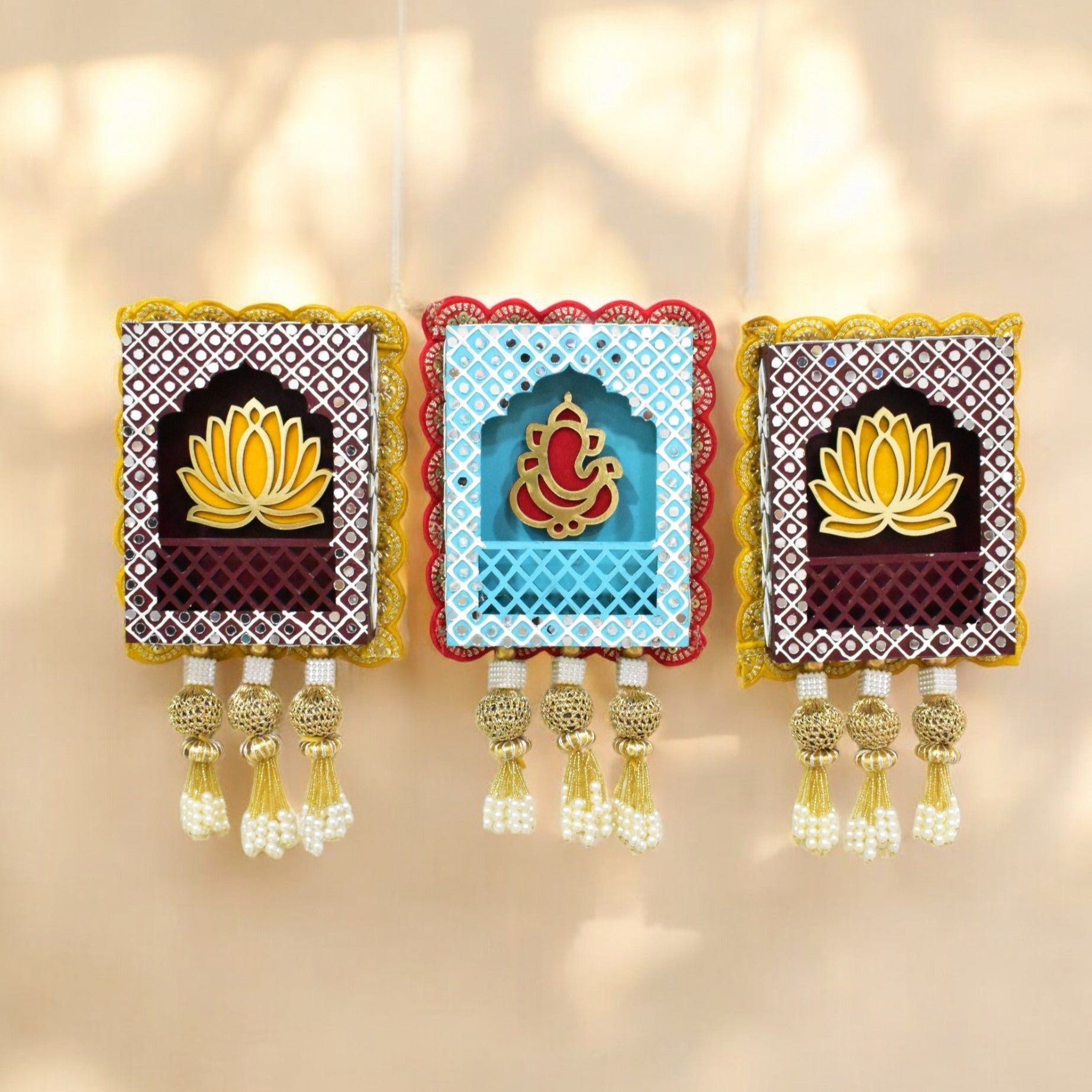 A set of three wall hangings jharokha featuring traditional Indian design with lotus motifs and Lord Ganesha, in colors red, blue, and yellow.