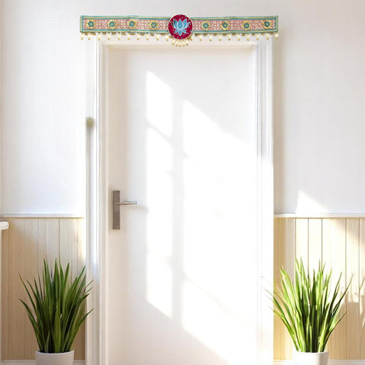 White door with decorative door hanging toran, plants on either side, and wooden paneling.