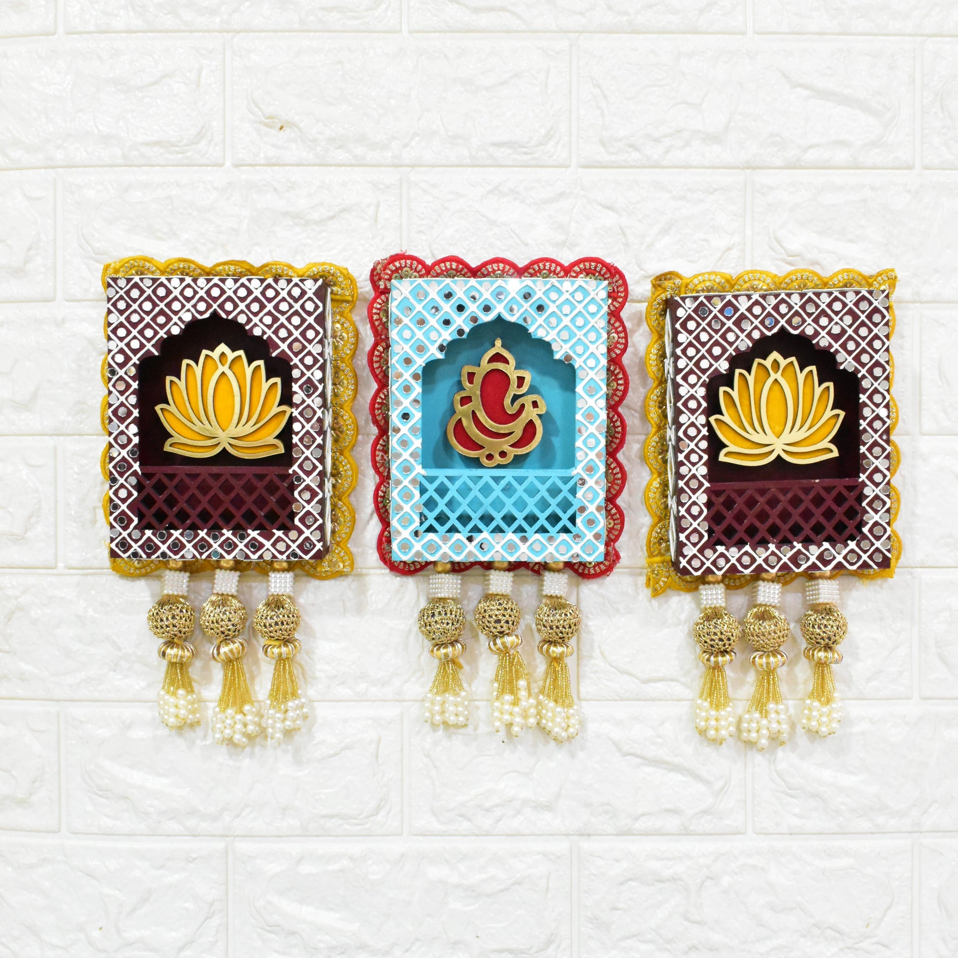 A set of three handcrafted wall hangings featuring Lord Ganesha with a lotus flower design, in blue, red, and gold colors, with decorative elements.
