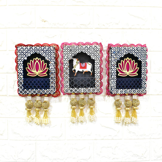 Three rectangular wall hangings featuring a combination of sacred Kamdhenu (cow) and Lotus Jharokha designs, with intricate patterns and gold-colored embellishments.