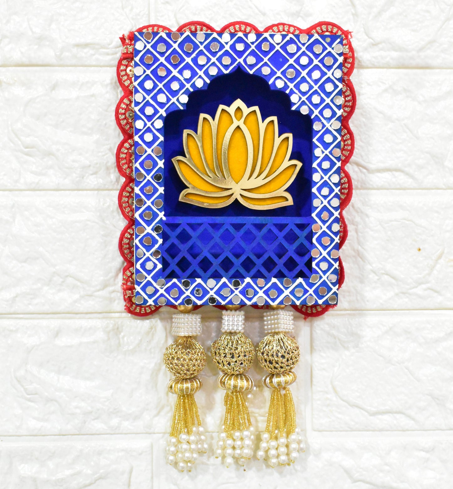 A Handcrafted Lotus Jharokha Wall Hanging with blue and red decorative patterns and a yellow lotus flower in the center, hanging against a white wall.