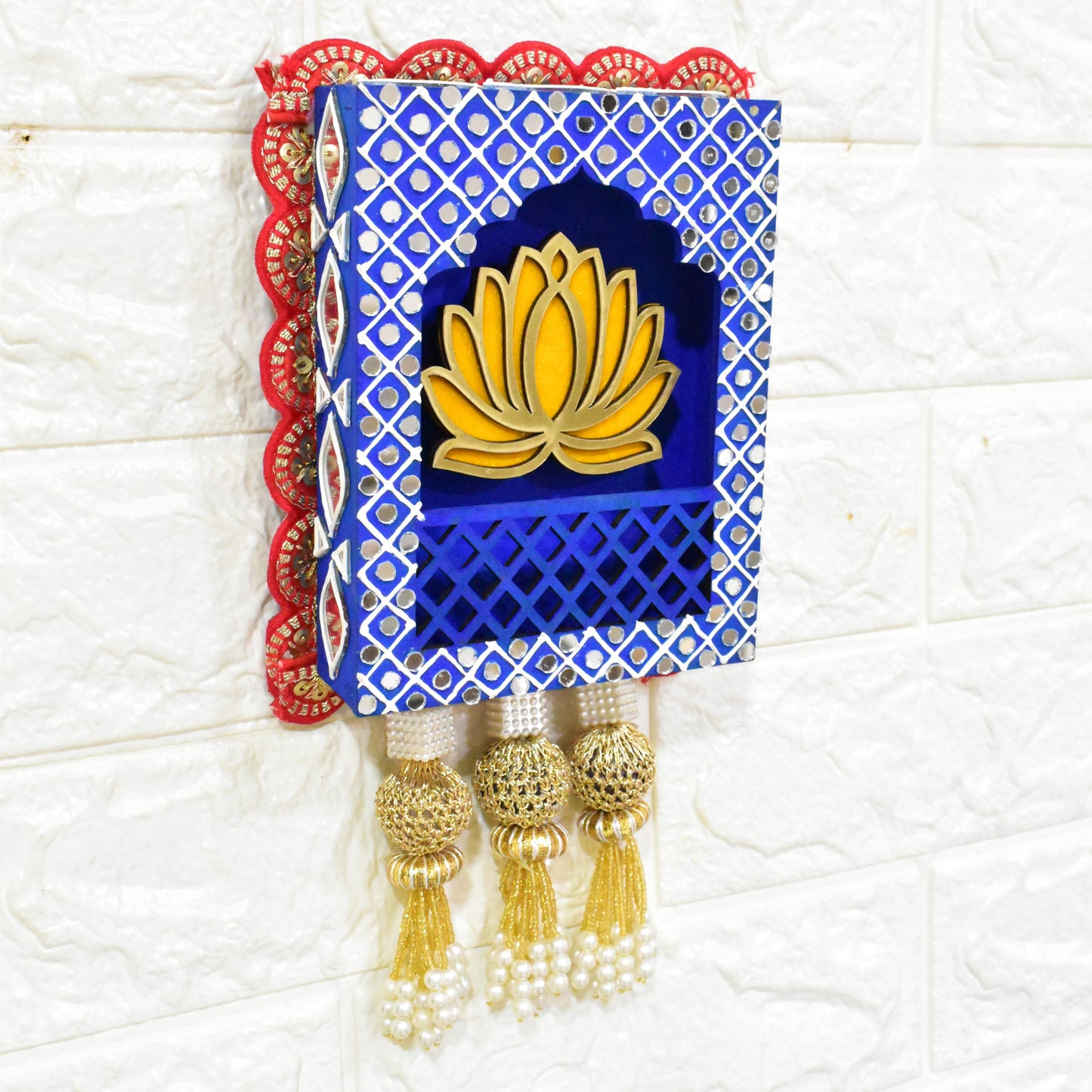 A Handcrafted Lotus Jharokha Wall Hanging with blue and red decorative patterns and a yellow lotus flower in the center, hanging against a white wall.