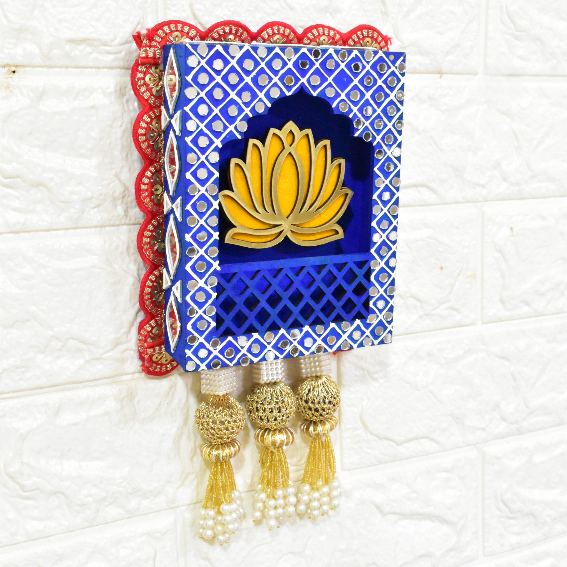 A Handcrafted Lotus Jharokha Wall Hanging with blue and red decorative patterns and a yellow lotus flower in the center, hanging against a white wall.