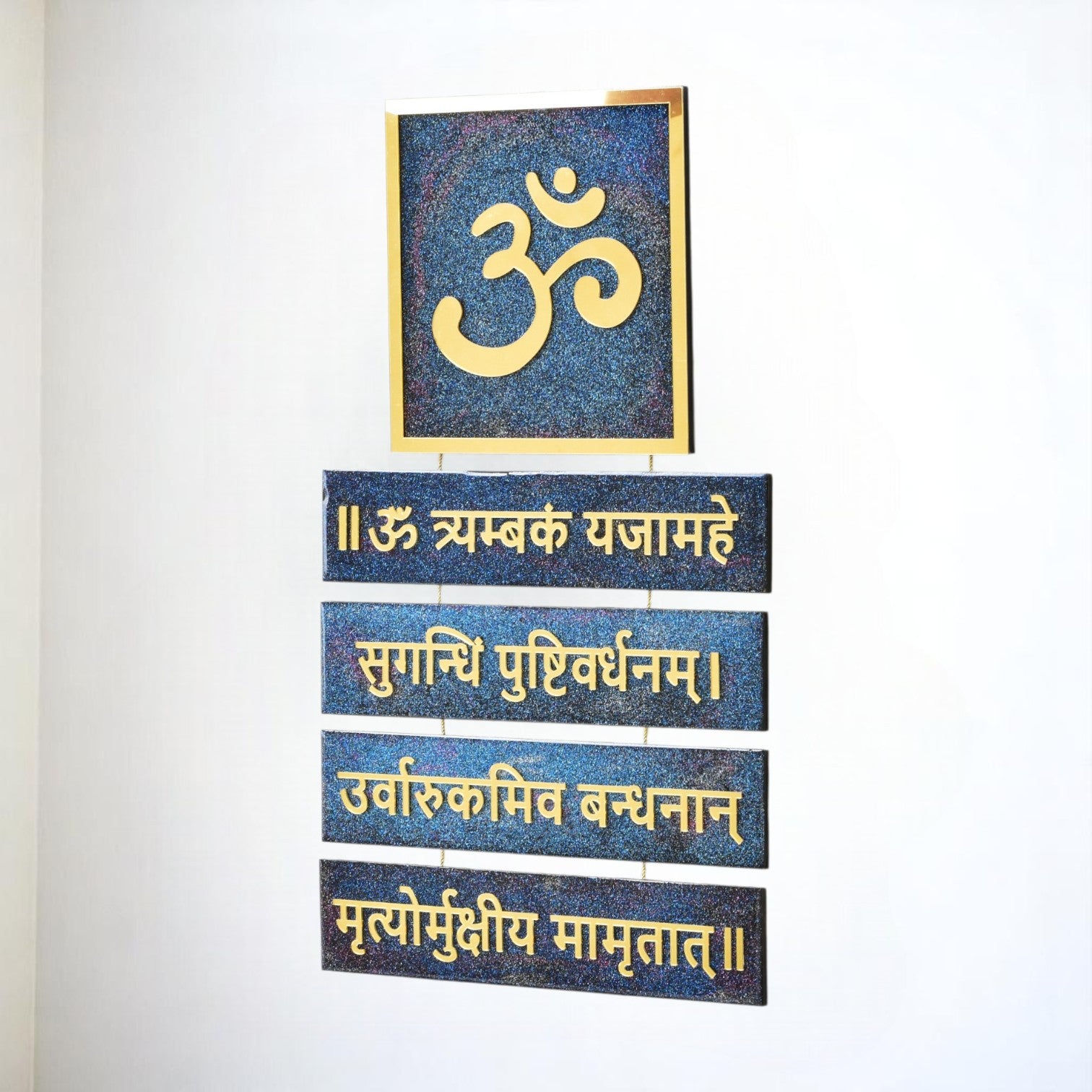 Decorative wall art with Om symbol and Maha Mrutyunjay Sanskrit text on blue tiles against a white background