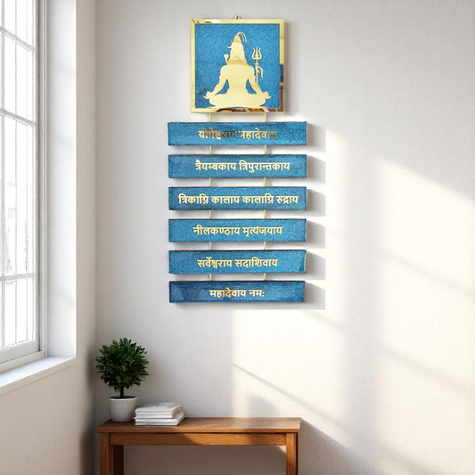 Decorative wall art with blue panels and gold Shiva figure in a room with a window and wooden table.