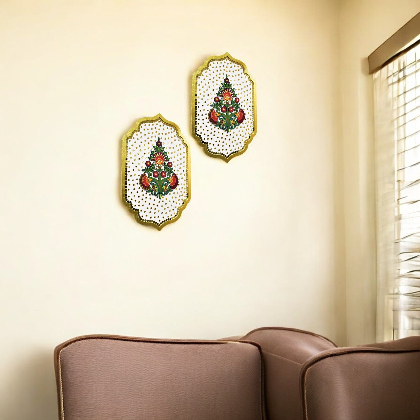 Two decorative wall art pieces with Christmas tree designs on a beige wall above a brown sofa.