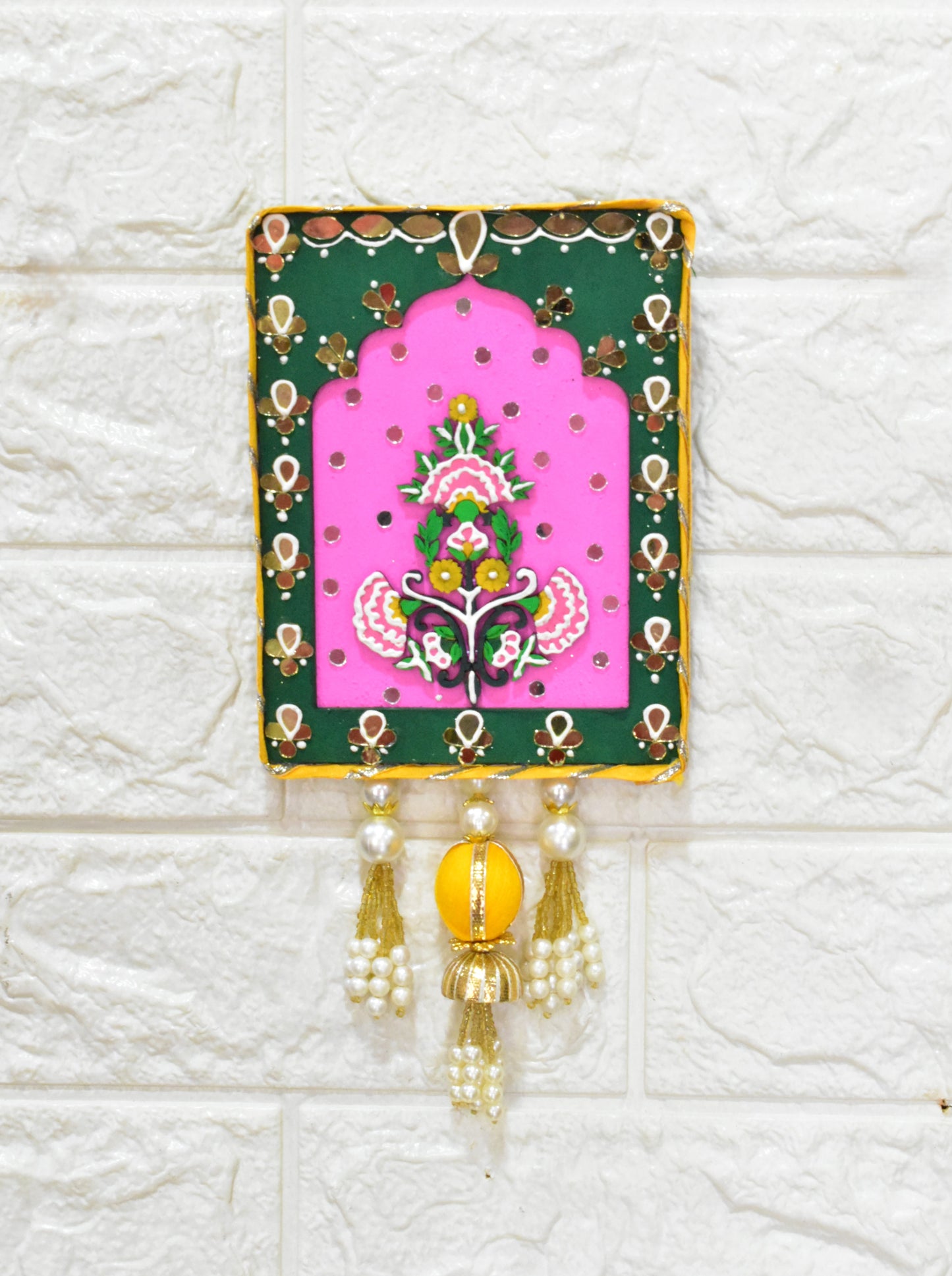 Decorative wall hanging with pink center and green border on a textured white background
