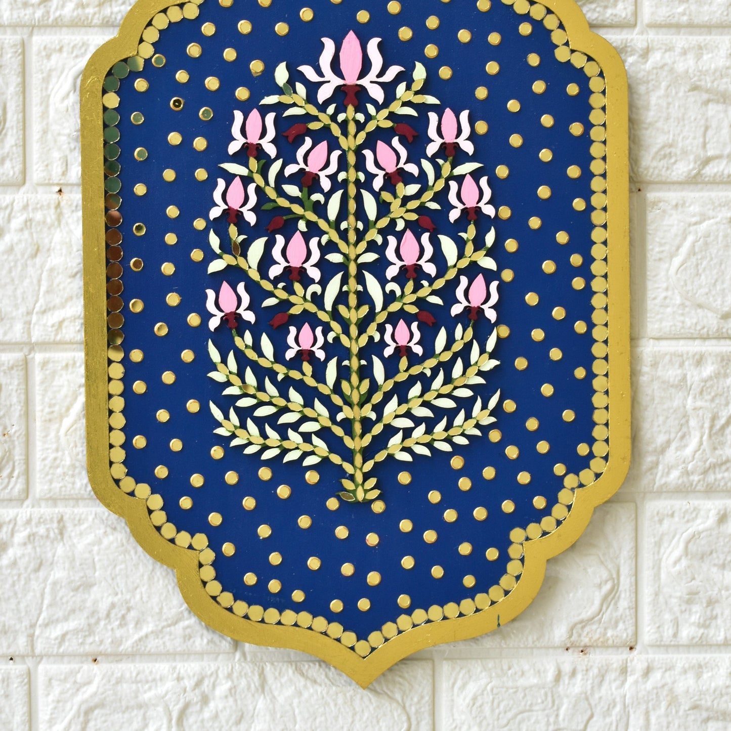 Decorative wall art with floral design on a blue background, mounted on a textured white wall.
