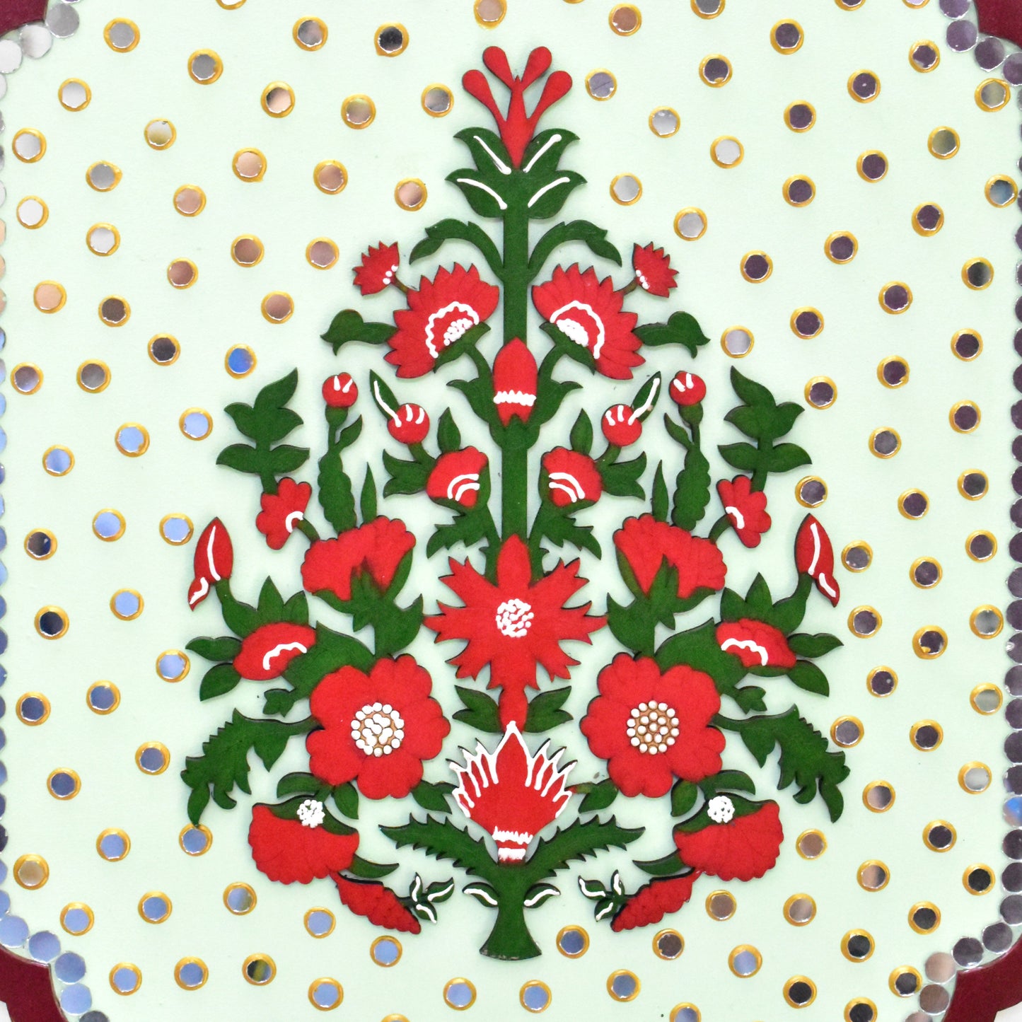 Decorative design with red flowers and green leaves on a white background with gold polka dots.