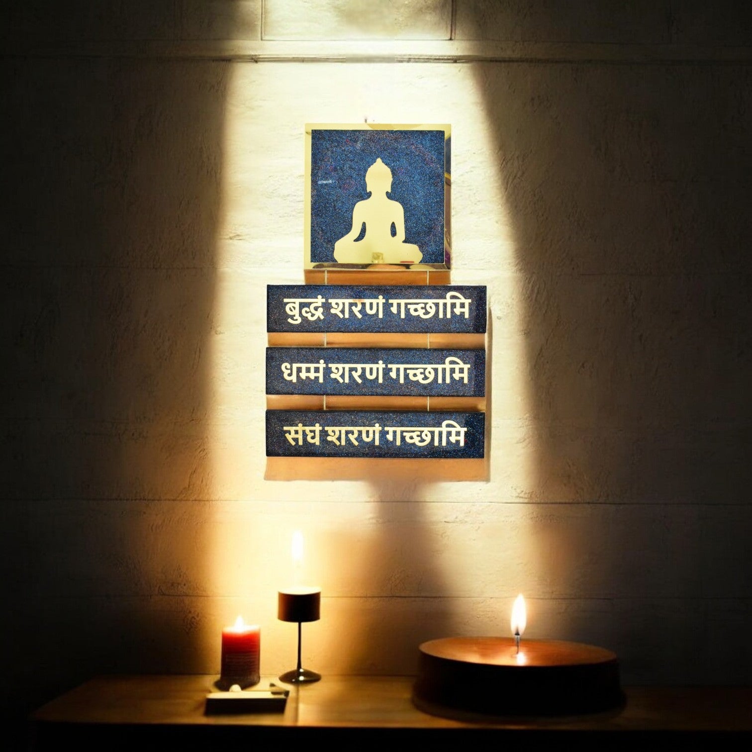 Decorative wall art with a Buddha figure and Mantra text, illuminated by candles in the pooja room.