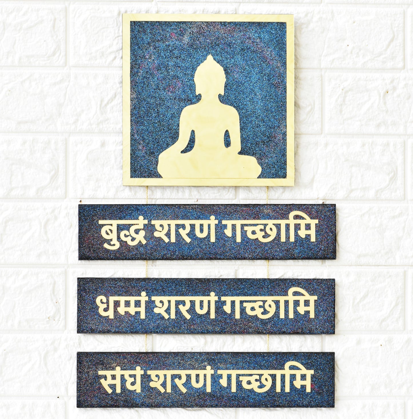 Framed picture of a Buddha silhouette with three mantra text panels on a white brick wall background.