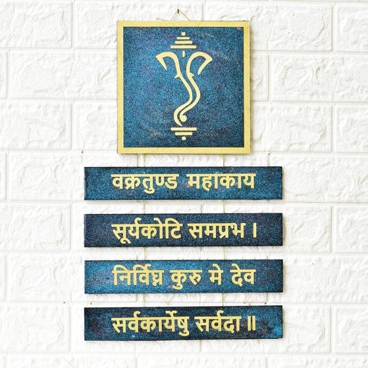 Decorative wall art with Ganesha symbol and Sanskrit text on a textured white wall.