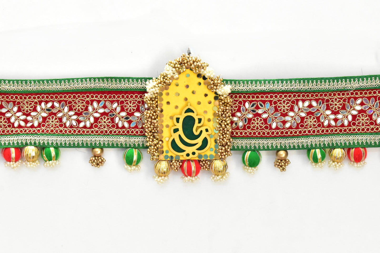 Decorative toran ganpati motif with gold, red, and green elements on a white background