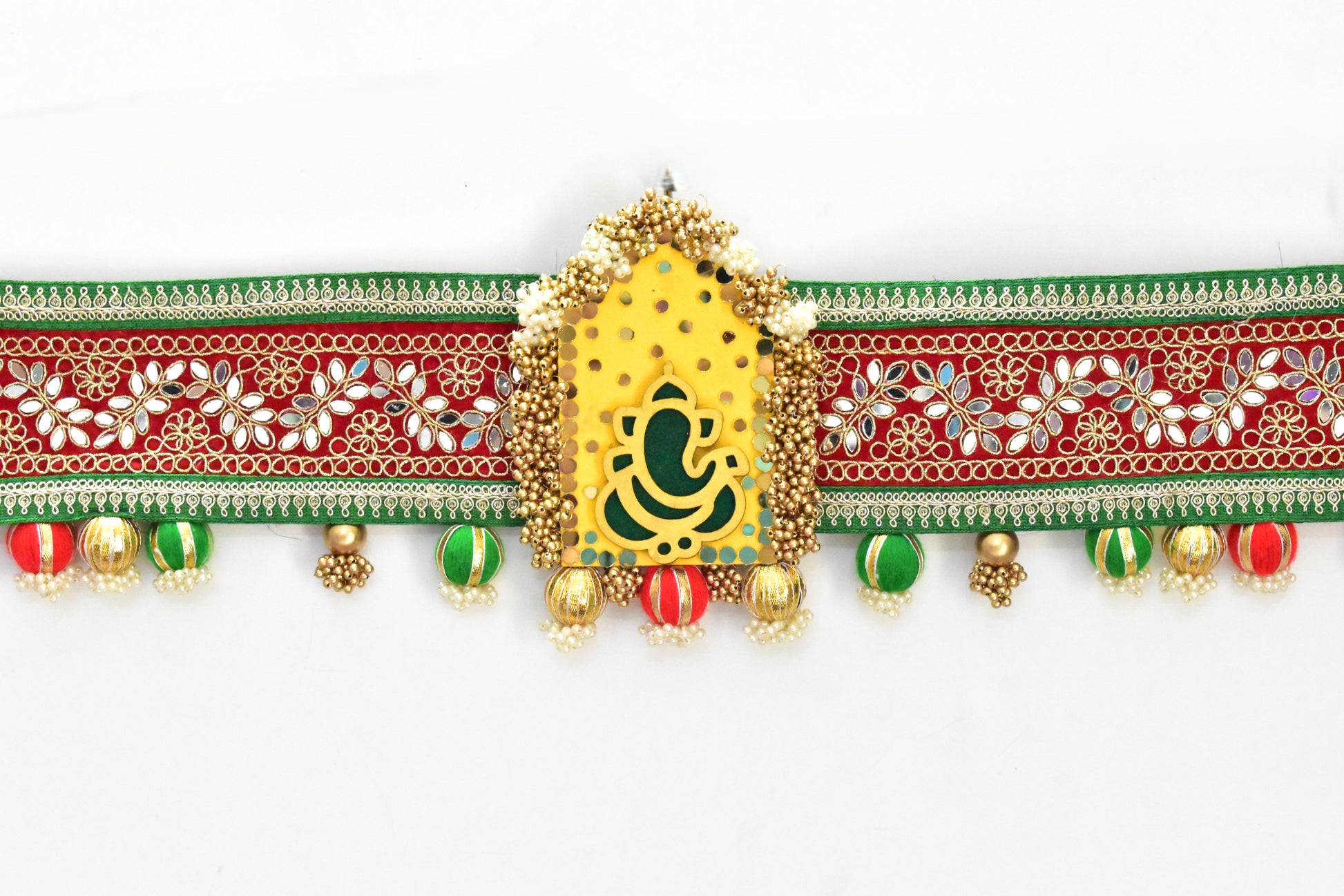 Decorative toran ganpati motif with gold, red, and green elements on a white background