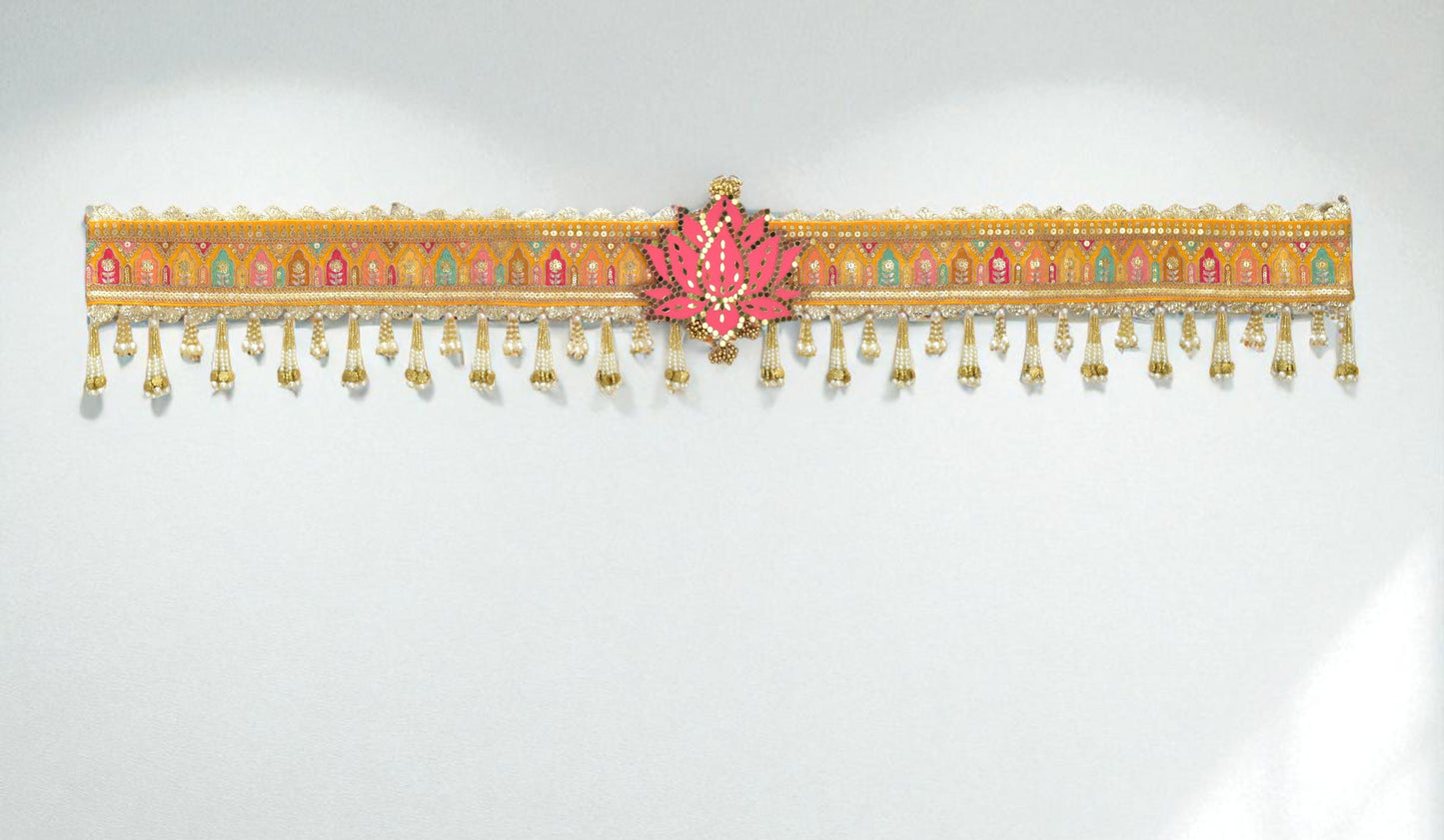 Decorative toran hanging with pink center and gold accents on a white background