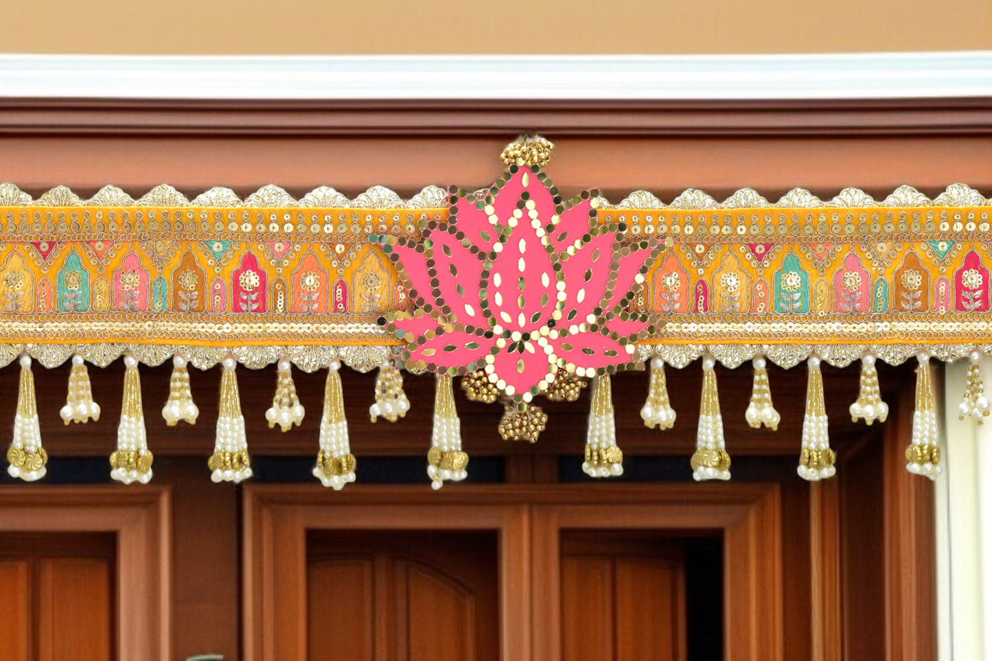 Decorative toran with pink lotus design and gold elements on a wooden door.