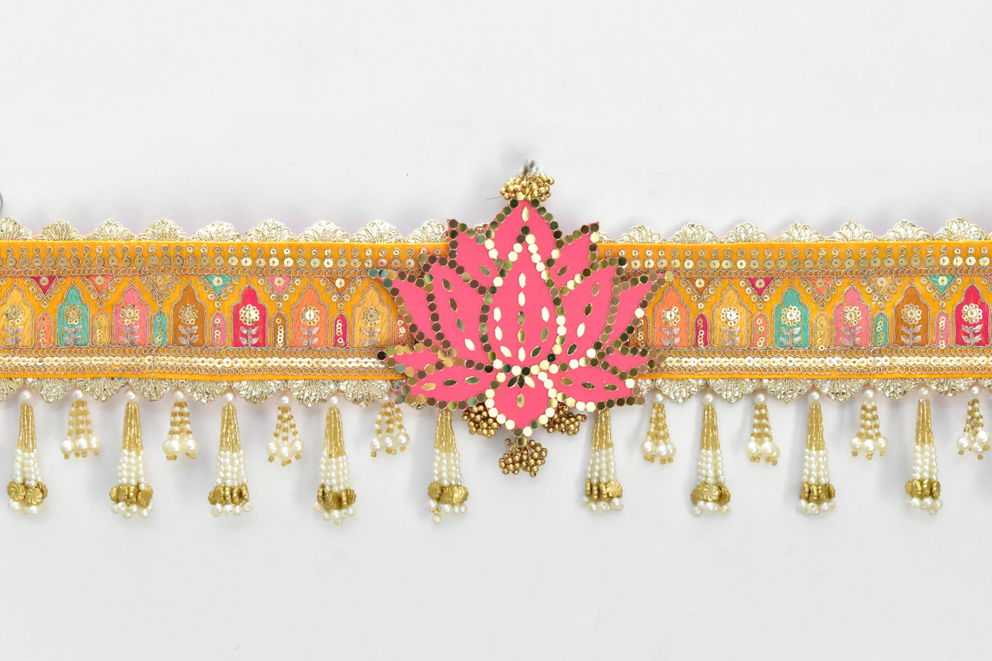 Decorative toran with pink floral design and gold tassels on a white background