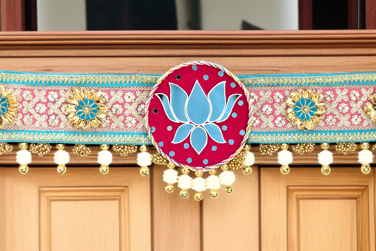 Decorative toran with a pink and blue lotus design on a wooden background