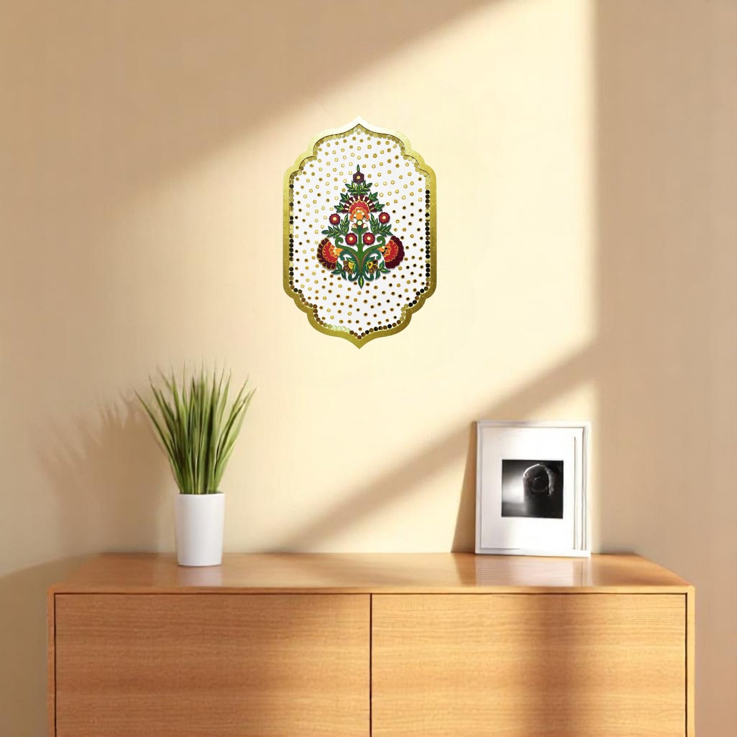 Decorative wall art piece on a beige wall above a wooden cabinet with a plant and framed picture.