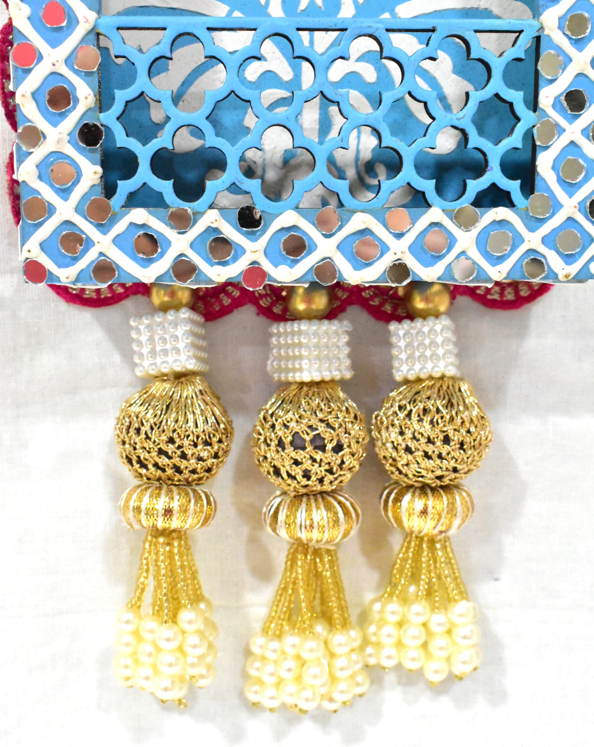 Close up of wall hanging with pearl tassels, featuring intricate floral cutwork and vibrant hand-painted patterns on premium MDF wood.