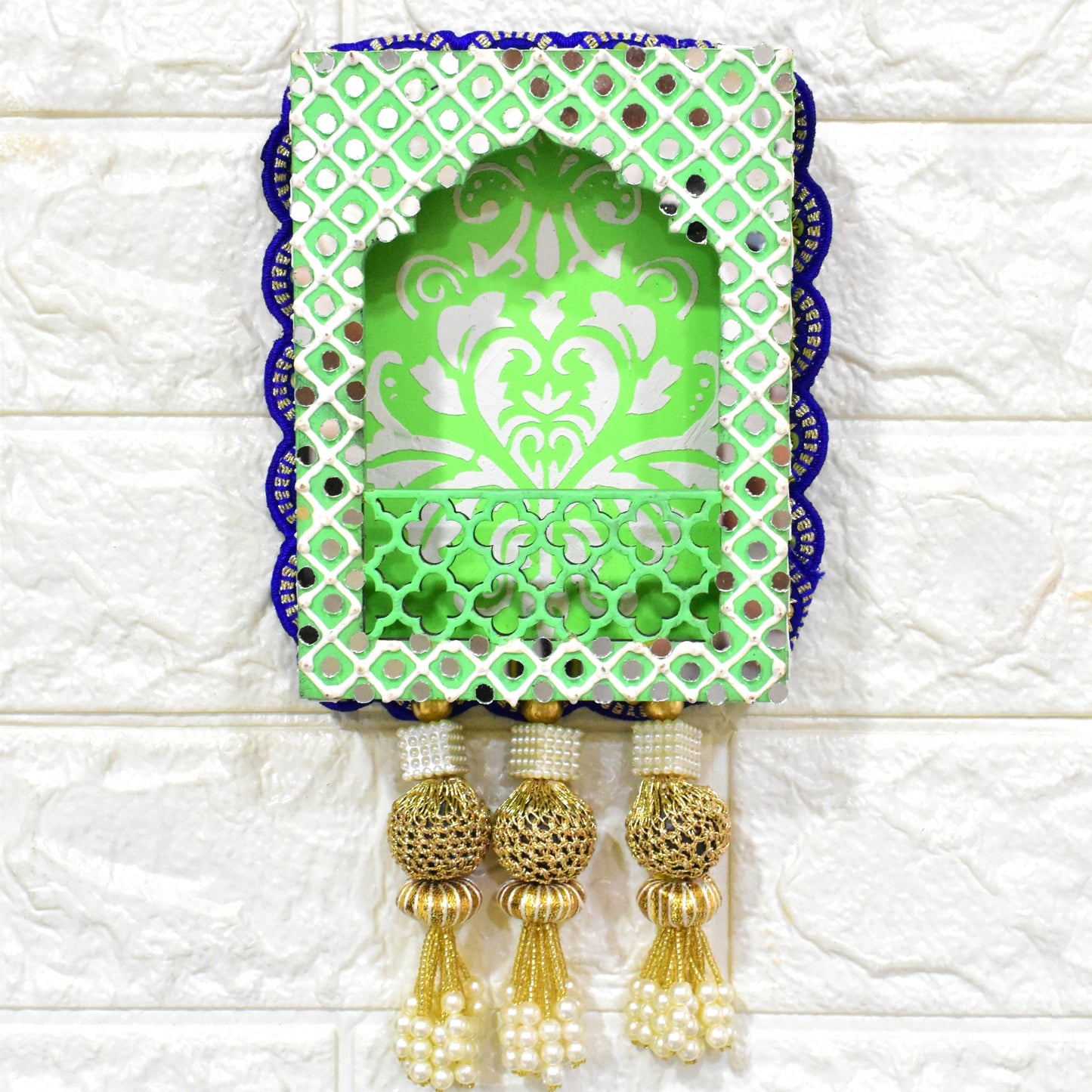 A handcrafted floral jharokha wall hanging with pearl tassels, featuring intricate floral cutwork and vibrant hand-painted patterns in green, and blue colors with golden accents.