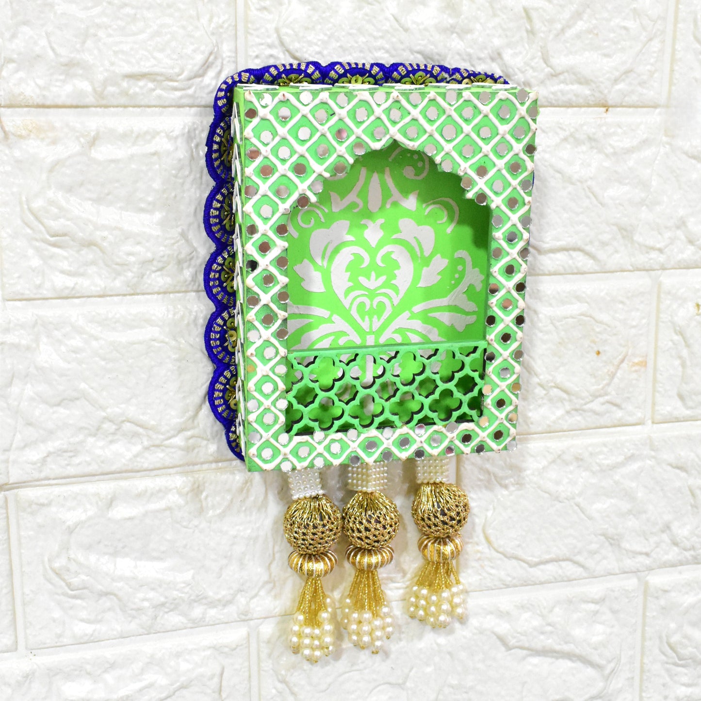 A handcrafted floral jharokha wall hanging with pearl tassels, featuring intricate floral cutwork and vibrant hand-painted patterns in green, and blue colors with golden accents.