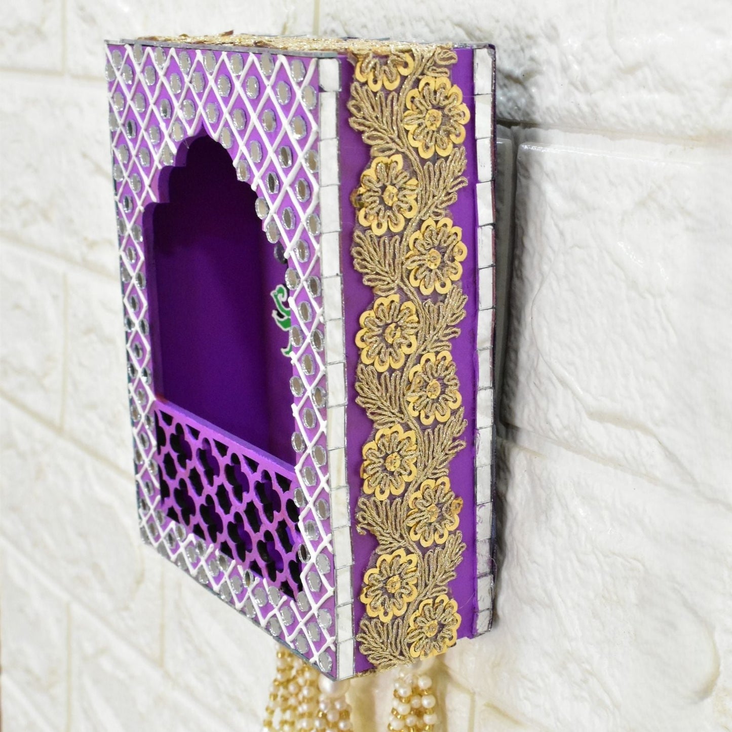 Side angle of decorative purple box jharokha with gold floral patterns on a textured white background