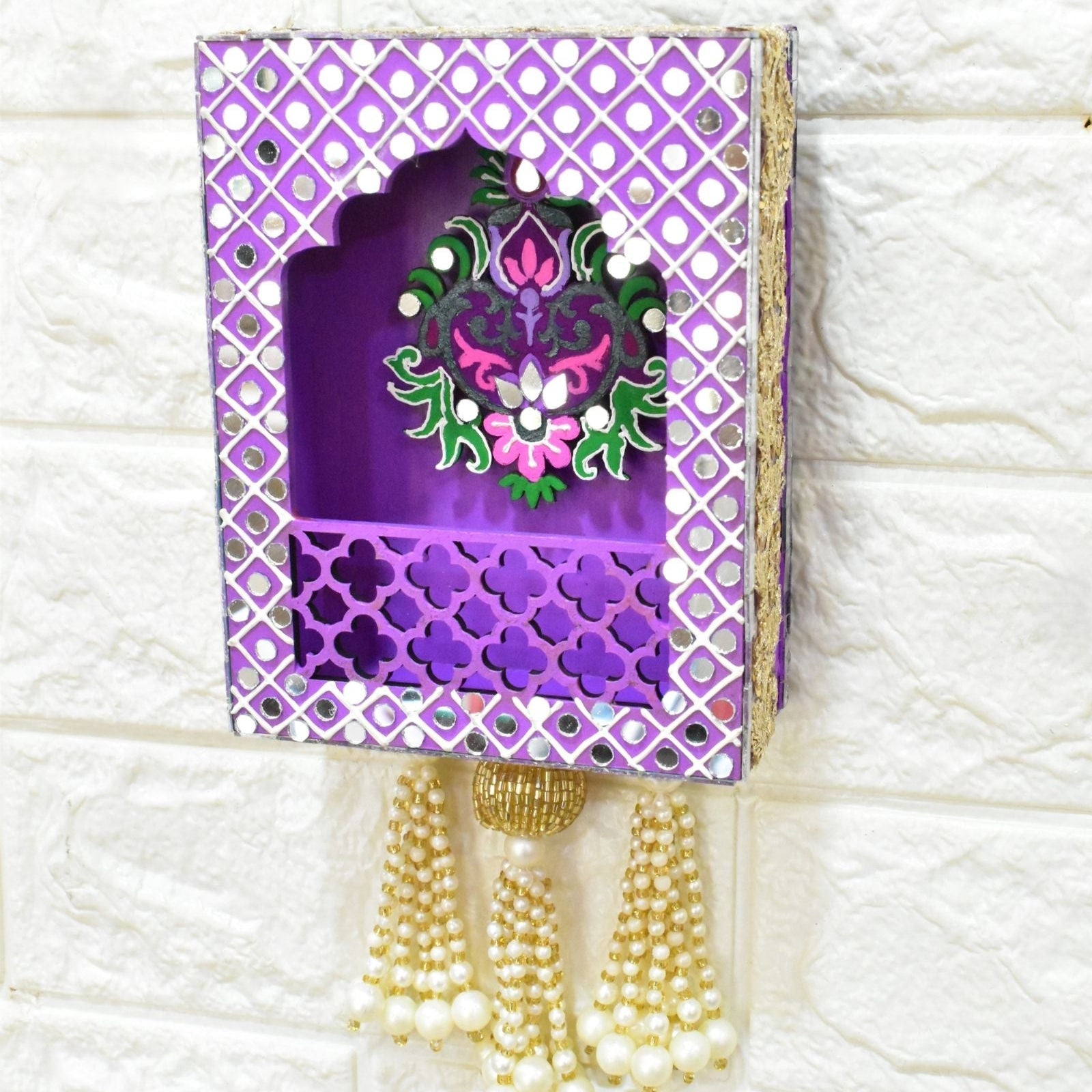 Decorative purple jharokha wall hanging with floral design and tassels on a white textured background